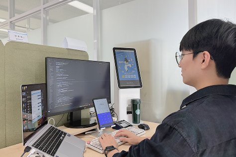 책상 위 모니터와 태블릿, 휴대폰에 렛미업 화면을 띄워 두고 개발자가 작업하고 있다.