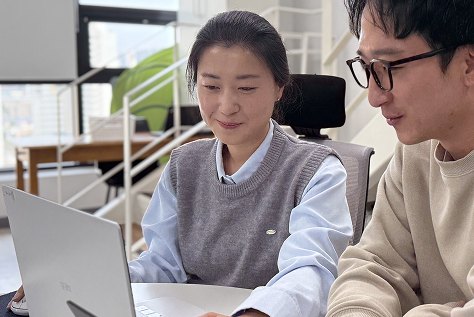 두 사람이 노트북 화면을 함께 보며 이야기하고 있다.